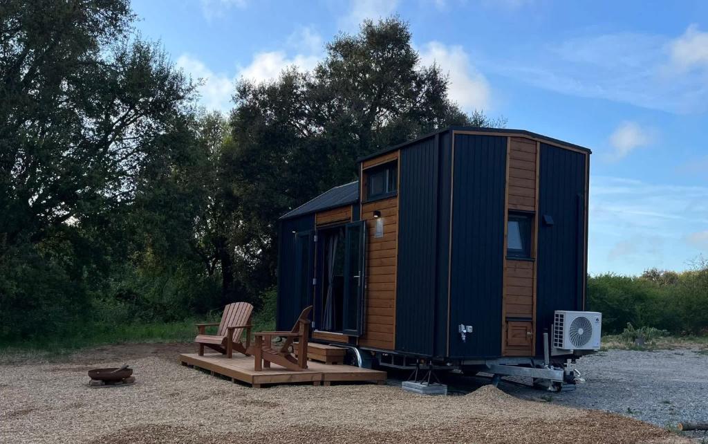 a blue tiny house with a bench and a chair at Casa do Cipreste by Tiny Away in São Teotónio