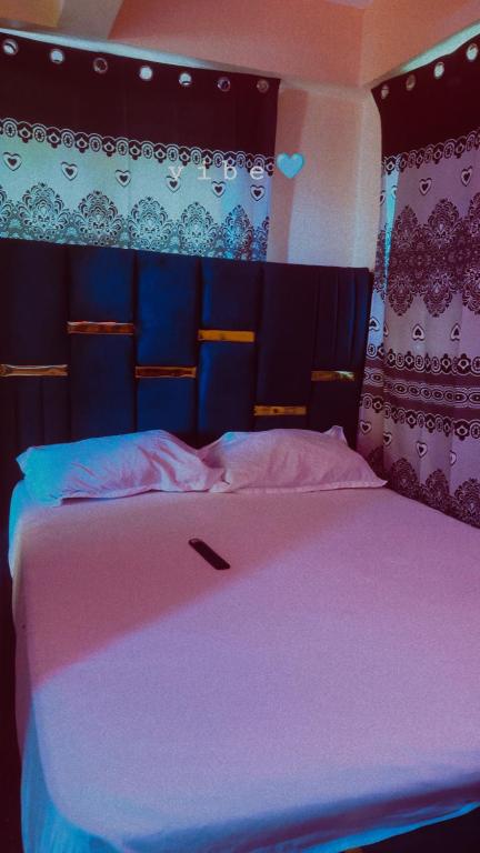 a bedroom with a large bed with a pink blanket at Leisure guest in Diani Beach