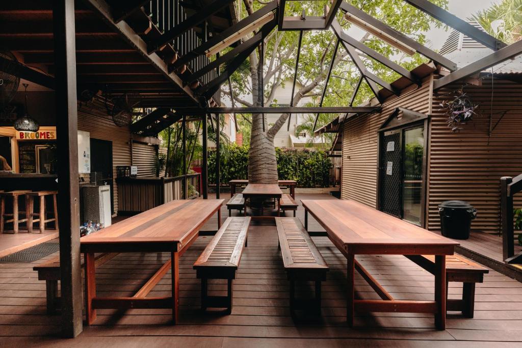 a group of benches on a deck with a tree at Kimberley Travellers Lodge in Broome