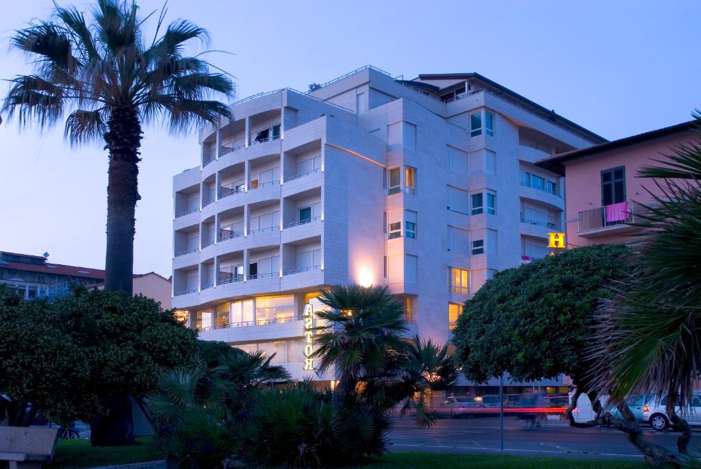 un grand bâtiment avec un palmier devant lui dans l'établissement Hotel Sina Astor, à Viareggio