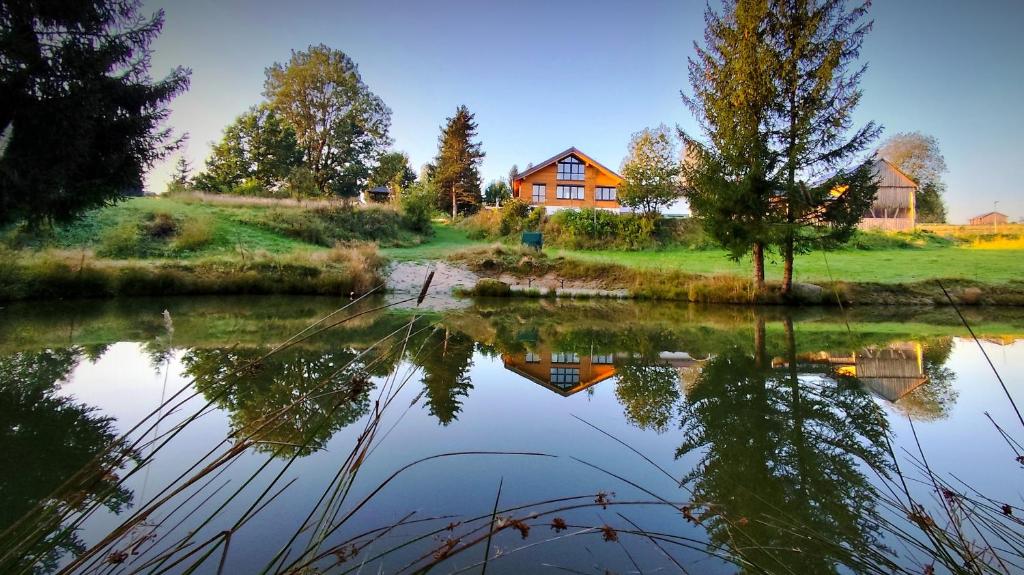a house on a hill next to a body of water at Ferienwohnung Abendsonne in Nagel