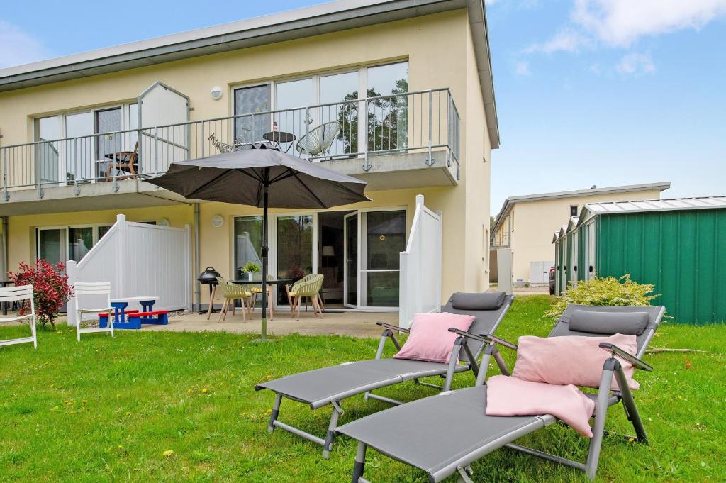 a group of chairs and an umbrella in front of a house at Lieblingsinsel in Graal-Müritz