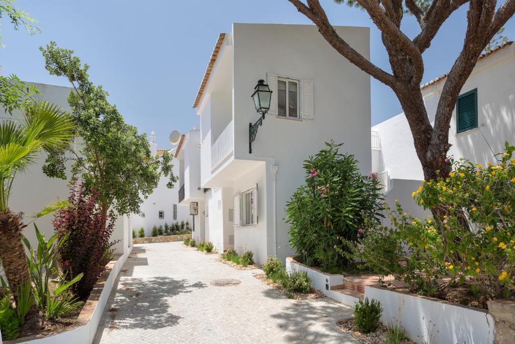 a street of white houses with trees and plants at Villa Leeroy in Almancil