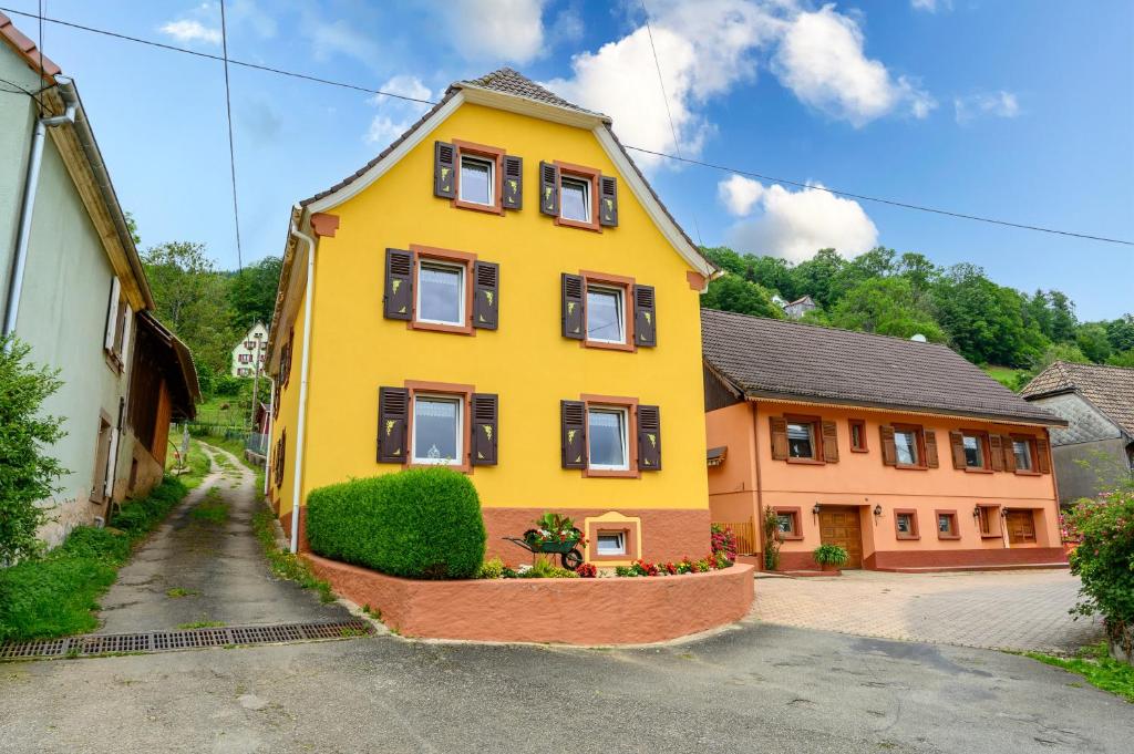 a yellow house with black windows on a street at Villa Balboa in Sondernach