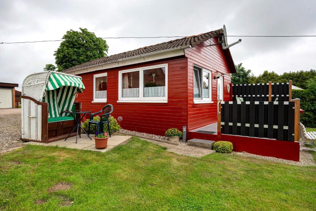 a red tiny house with a gazebo at Ferienhaus Landhaus Loose in Schashagen