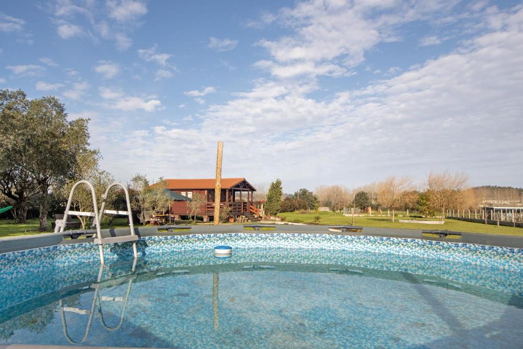 a large swimming pool in a park with a house at Casa da Lagoa Pateira in Fermentelos