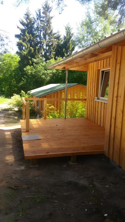 a wooden deck on the side of a house at Bungalows im Grünen in Lychen