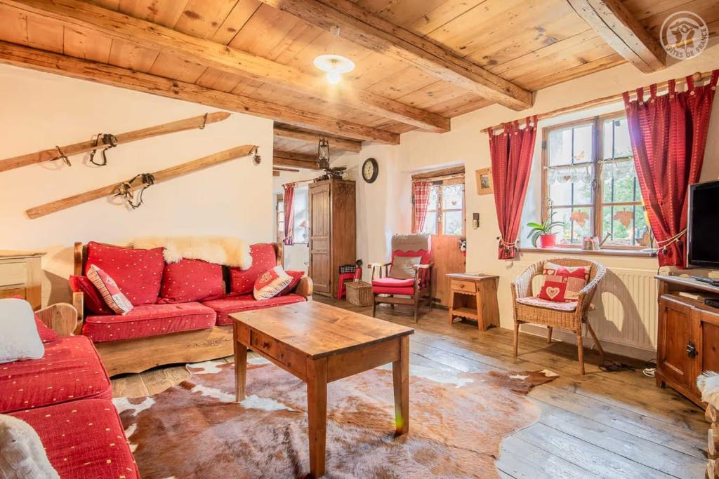 a living room with a red couch and a table at Chalet de Marie proche des Saisies in Queige