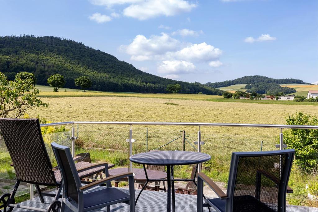 a table and chairs on a deck with a view of a field at Haus Lerchenweg B in Bad Wildungen