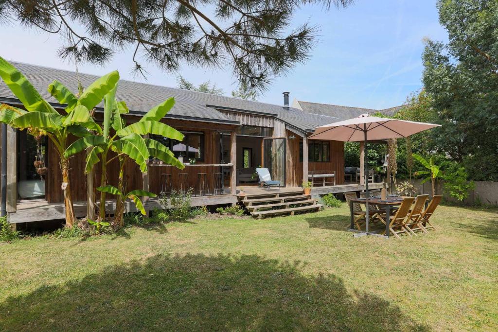 a wooden house with a table and an umbrella at Maison Vacances Gaetan in Binic