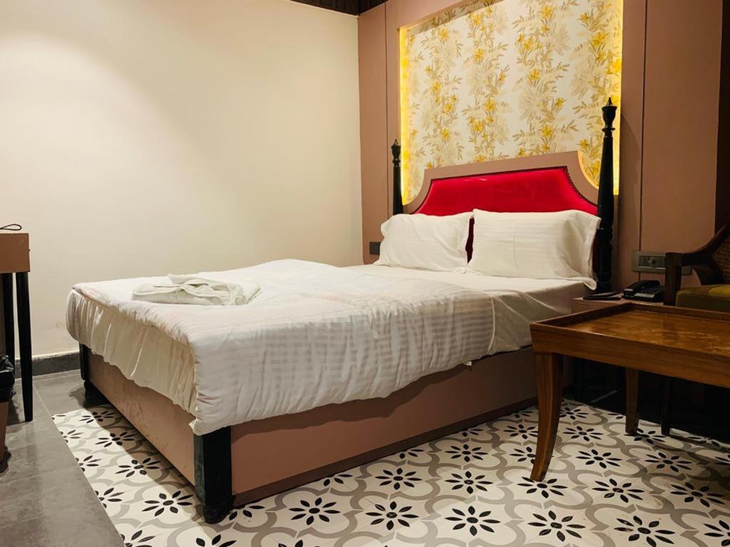 a bedroom with a large bed with a red headboard at Hotel The Palassio in Kānpur