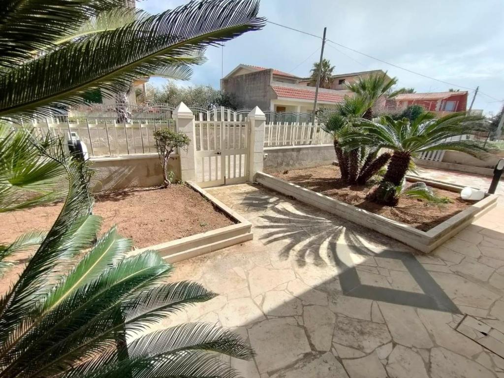 a backyard with a white fence and palm trees at Villetta Roby in Marina di Modica