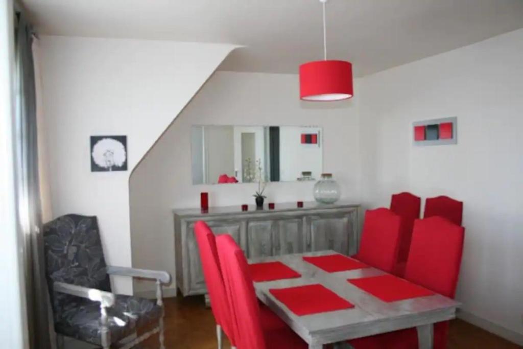 a dining room with red chairs and a table at Le Goéland in Sarzeau