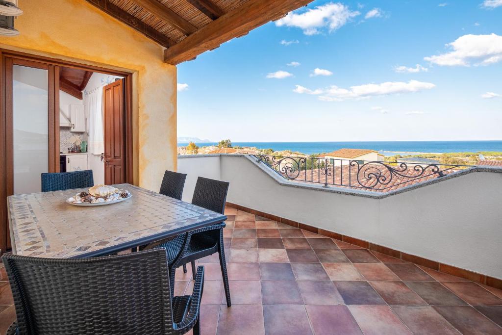 a table and chairs on a balcony with a view of the ocean at Appartamento Zeus in Tanaunella