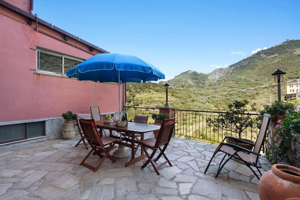 a table and chairs with a blue umbrella on a patio at Appartamento Aurora in Corniglia