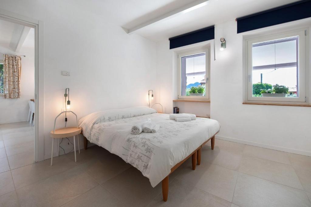a white bedroom with a bed and two windows at Casa Mavi in Corte Franca