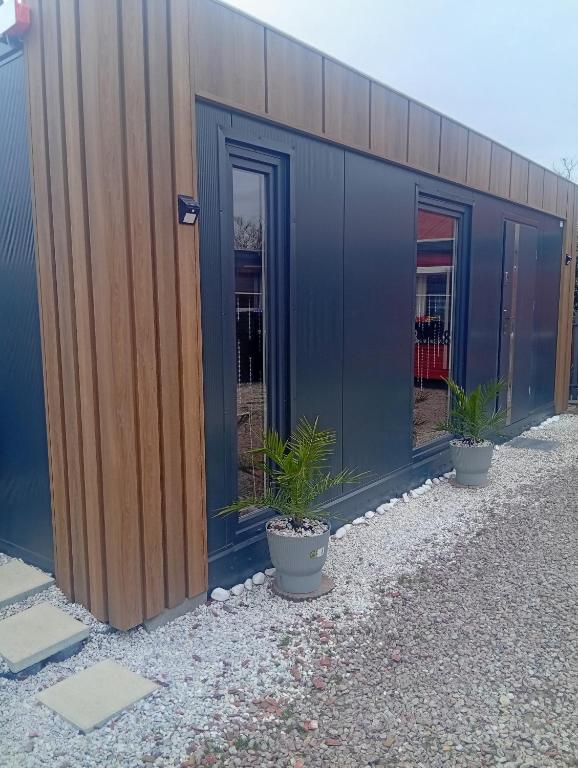 a blue building with potted plants in front of it at Domek modułowyBursztynek in Rewa
