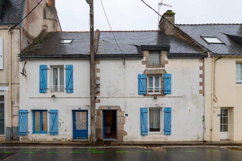 an old white house with blue shutters on a street at Maison Sarzeau Centre - La Bernache in Sarzeau