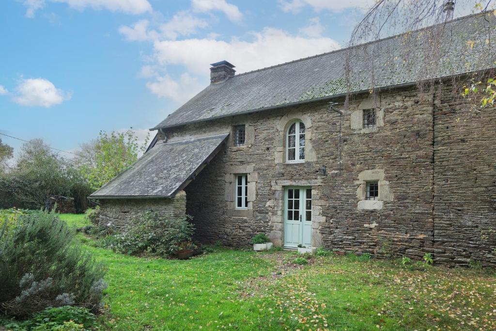 an old stone house in a field of grass at Ker Cado - Chambre d'hôtes in Mauron