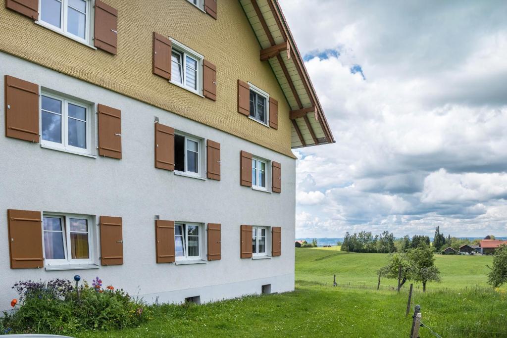 a building with windows and a field in the background at Haus Moritz in Heimenkirch