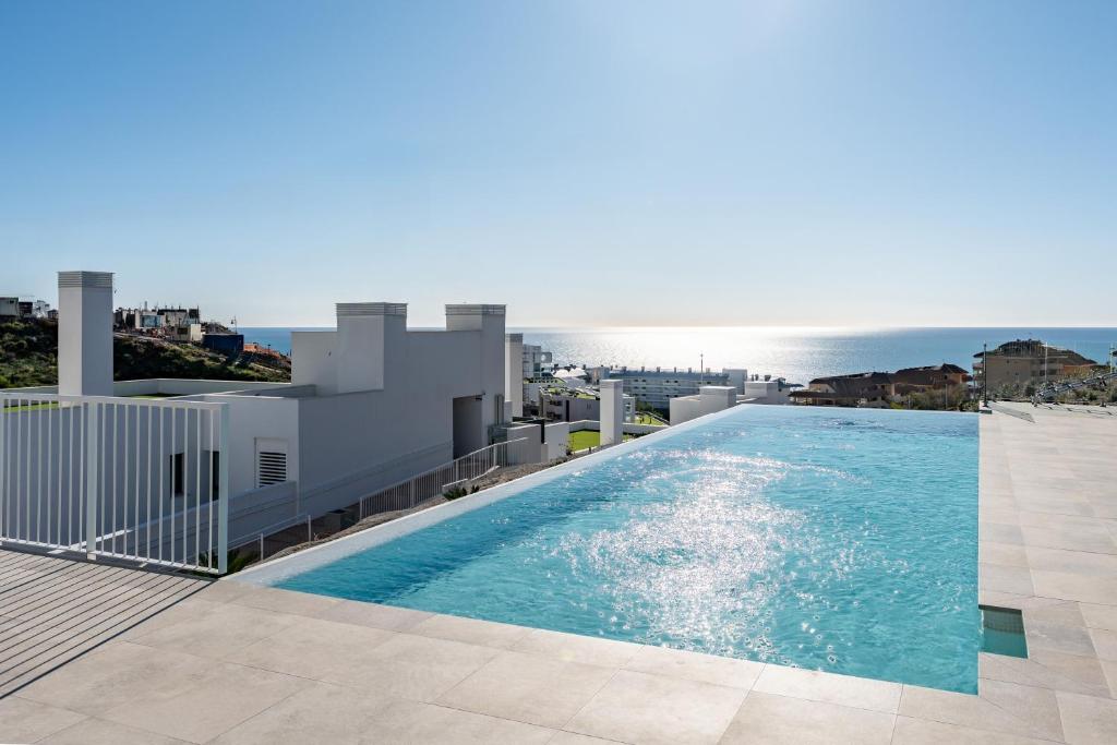 a swimming pool on the roof of a building with the ocean at Middle Views West in Fuengirola