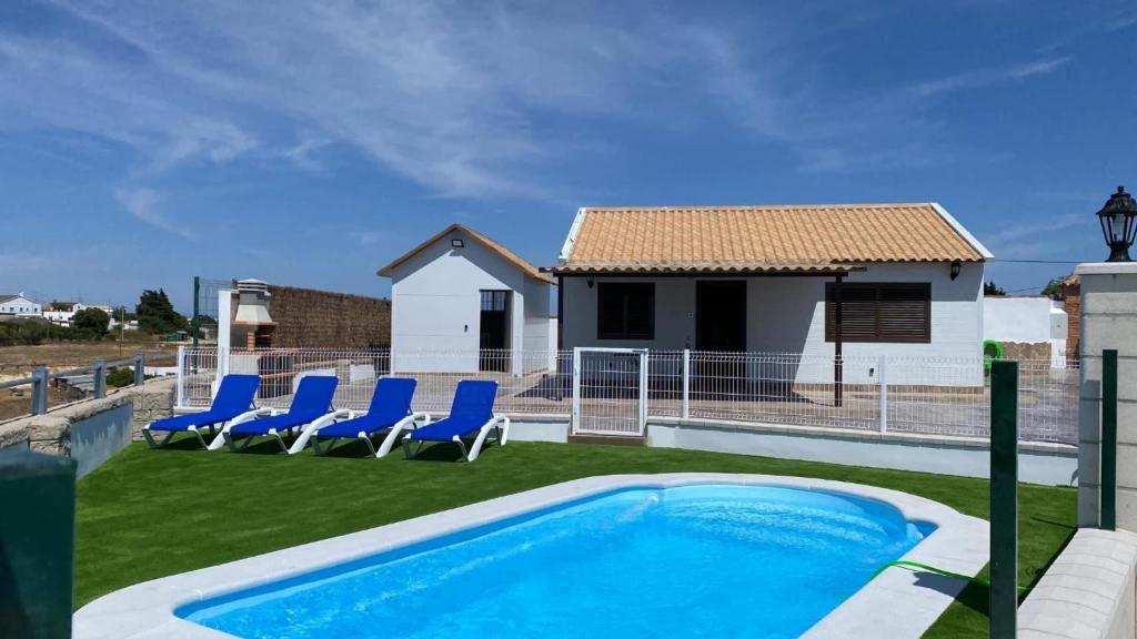 a swimming pool with blue chairs and a house at Casa Bellavistas in Vejer de la Frontera