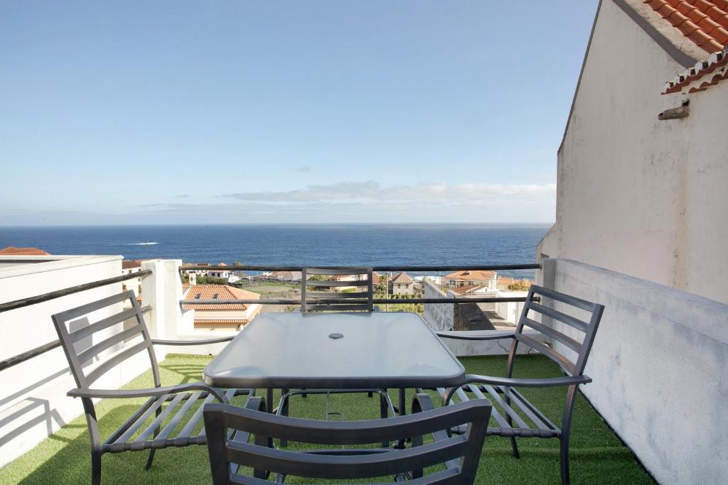 a table and chairs on a balcony with the ocean at Seaside Haven - Soulful Stays in Porto Moniz