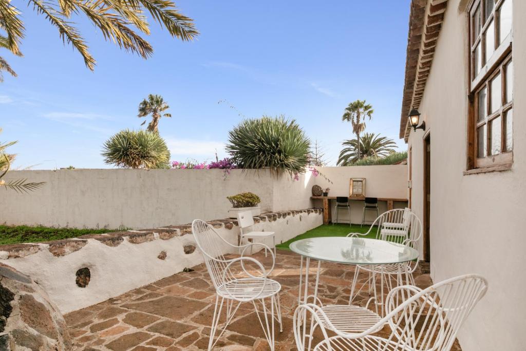 a patio with white chairs and a table at Casa Canaria Finca Real in Las Lagunas