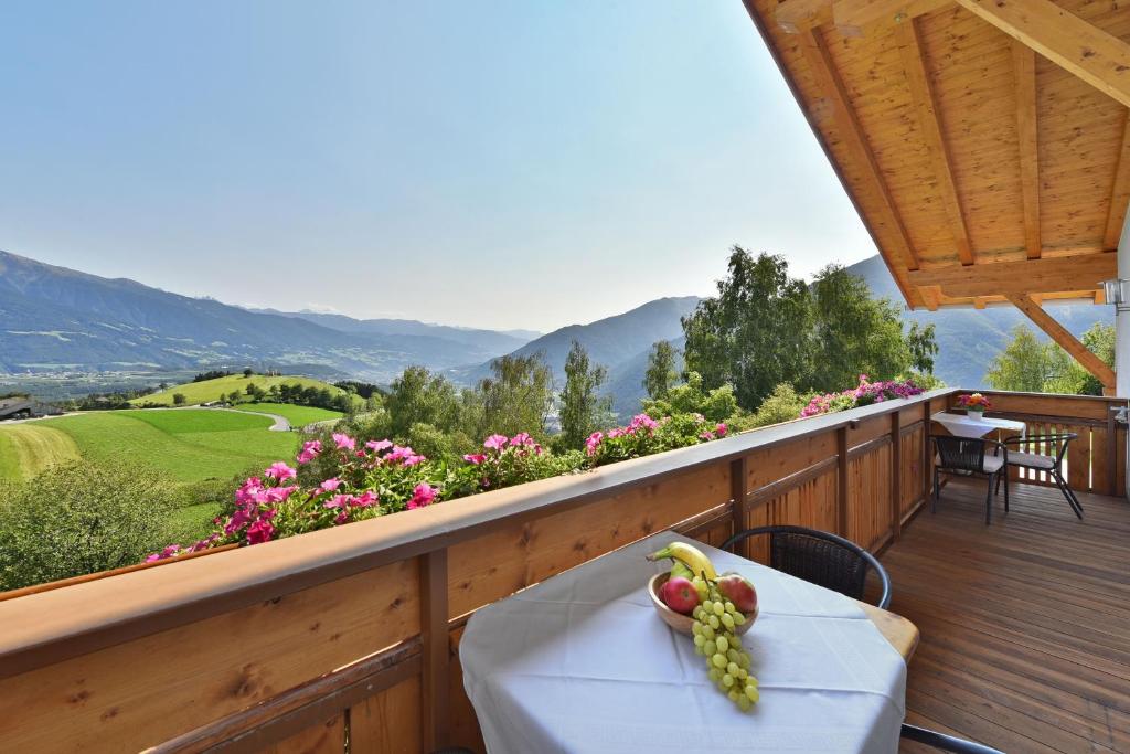 a table with a bowl of fruit on a wooden balcony at Apartment Dolomitenblick in Mühlbach