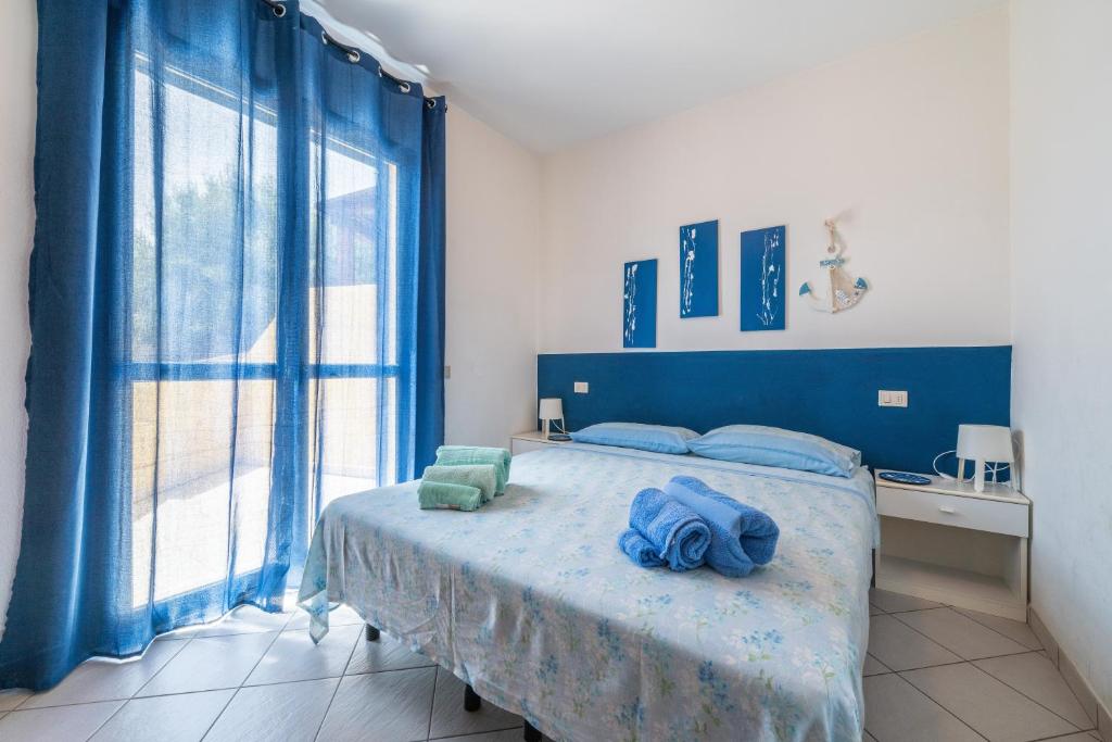a bedroom with a blue bed and a large window at Casa Vacanza Casi 2 in Villasimius