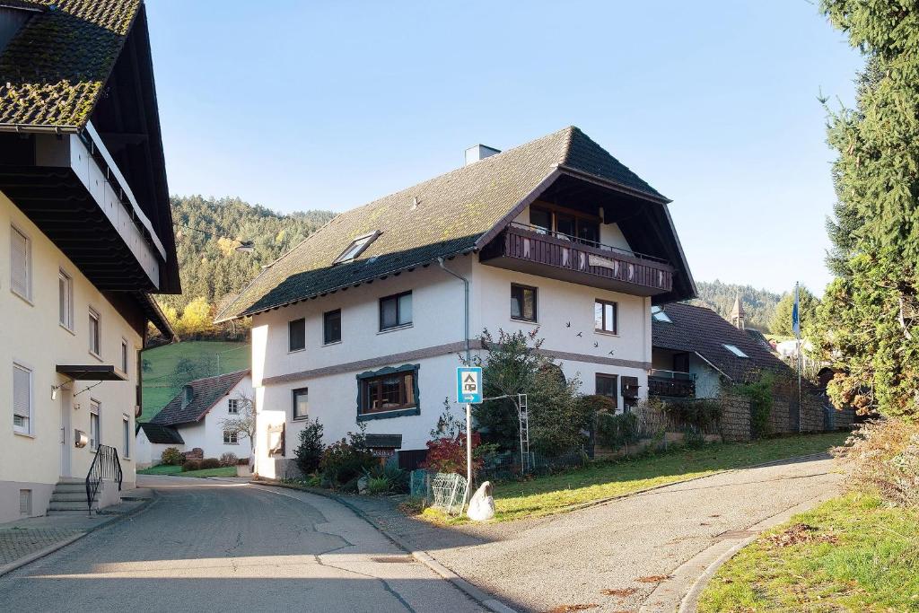 a large white house with a gambrel roof on a street at Ferienwohnung Waldblick in Simonswald