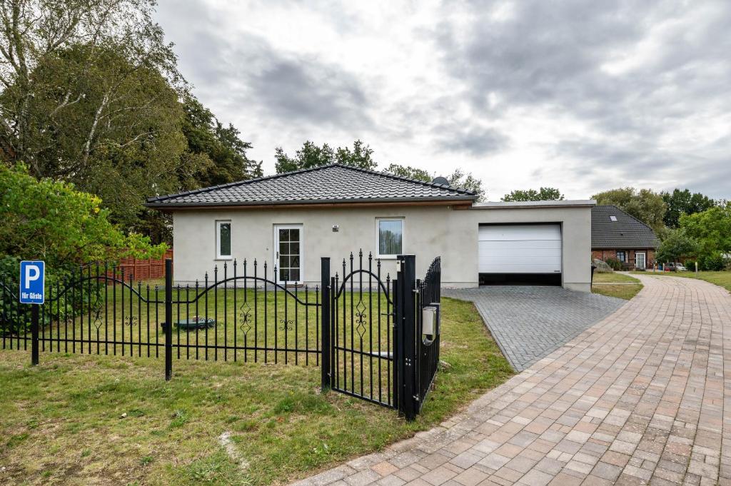 a white house with a gate and a driveway at Moderner Bungalow, rollstuhlgerecht in Warnow