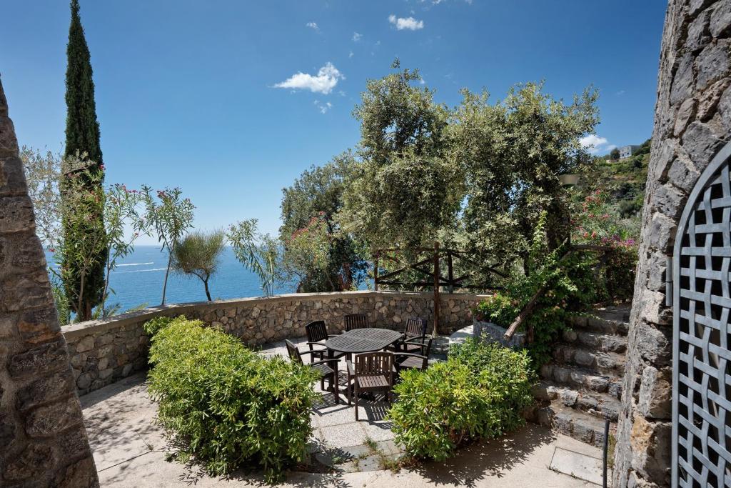 a patio with a table and chairs in a stone wall at Suite Tramonto in dependance in Conca dei Marini