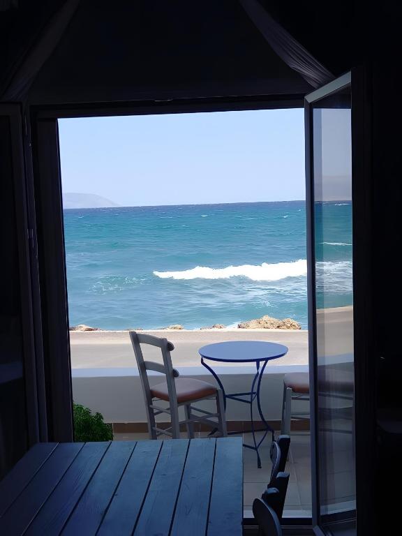 a view of the beach from a room with a table and chairs at I Have A Dream in Agia Pelagia
