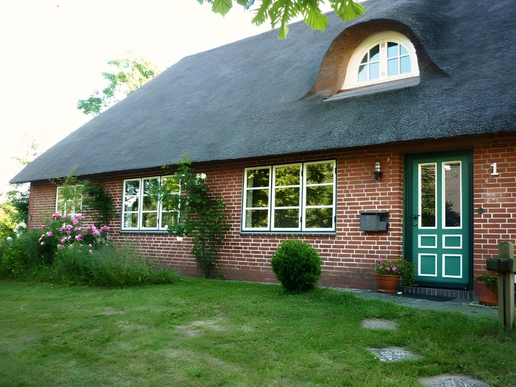 a red brick house with a green door and window at Ferienhaus Osterdeich in Neukirchen