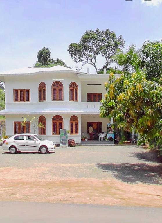 a white car parked in front of a house at Alhind Residency , Valara, Munnar in Munnar