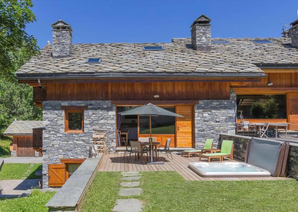 a stone house with a deck and patio at Chalet Du Houx in Les Allues