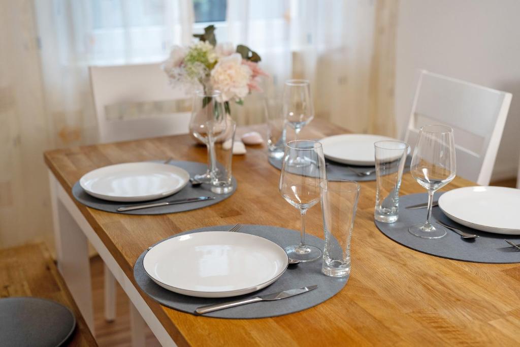 a wooden table with plates and wine glasses on it at Fewo unter der Kirche in Herbolzheim