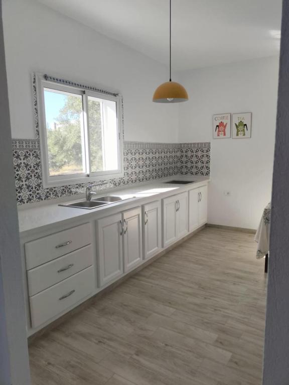 a white kitchen with a sink and a window at Quiet house with garden in Sakiet ez Zit