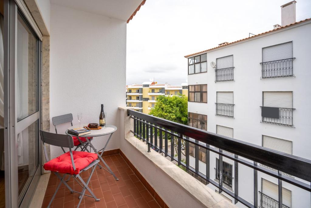 a balcony with a table and chairs and a window at Apartamento Escadinhas in Lagos