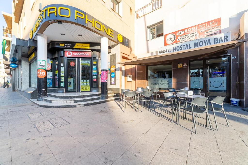 an empty street with tables and chairs in front of buildings at Hostal Moya in Roquetas de Mar