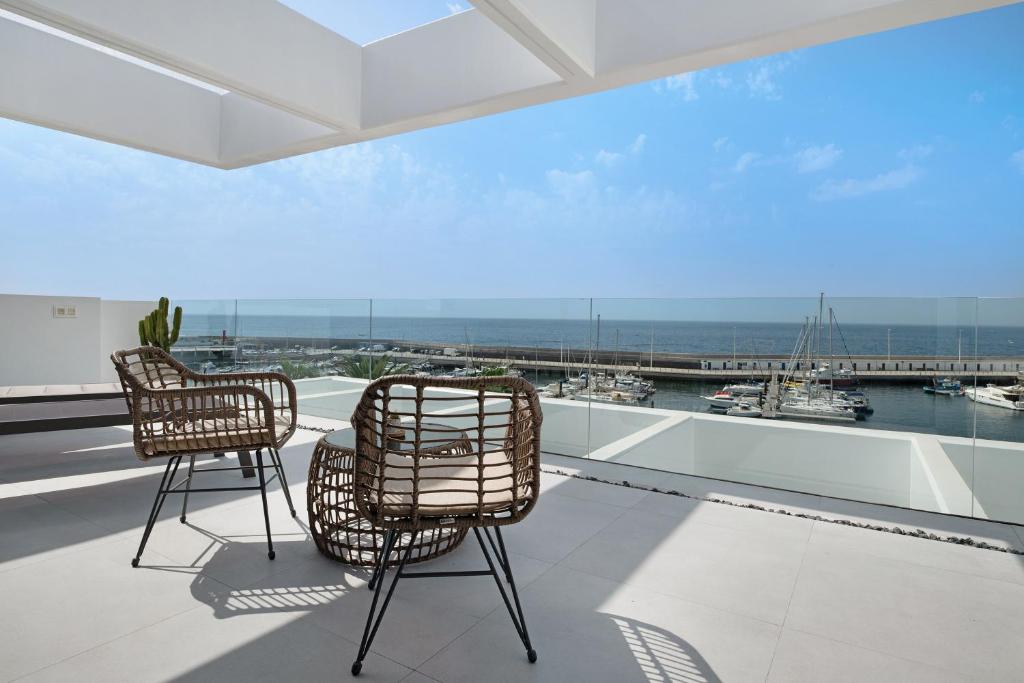 a balcony with two chairs and a view of a harbor at Suite Horizonte in Puerto del Carmen