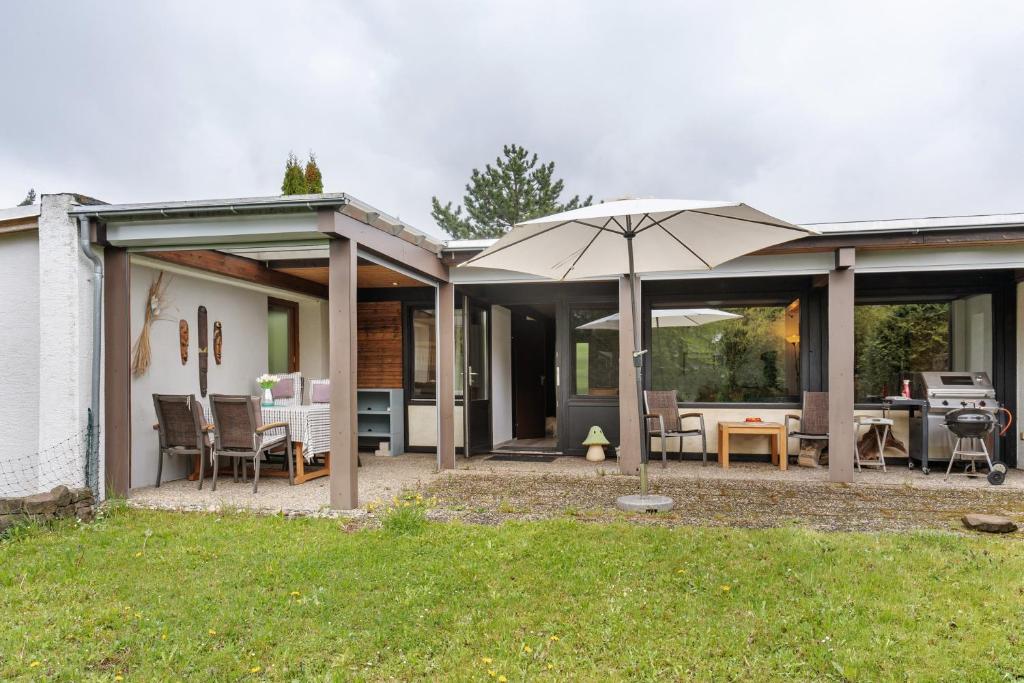 a house with a patio with an umbrella at Bungalow Nordschwarzwald in Schellbronn