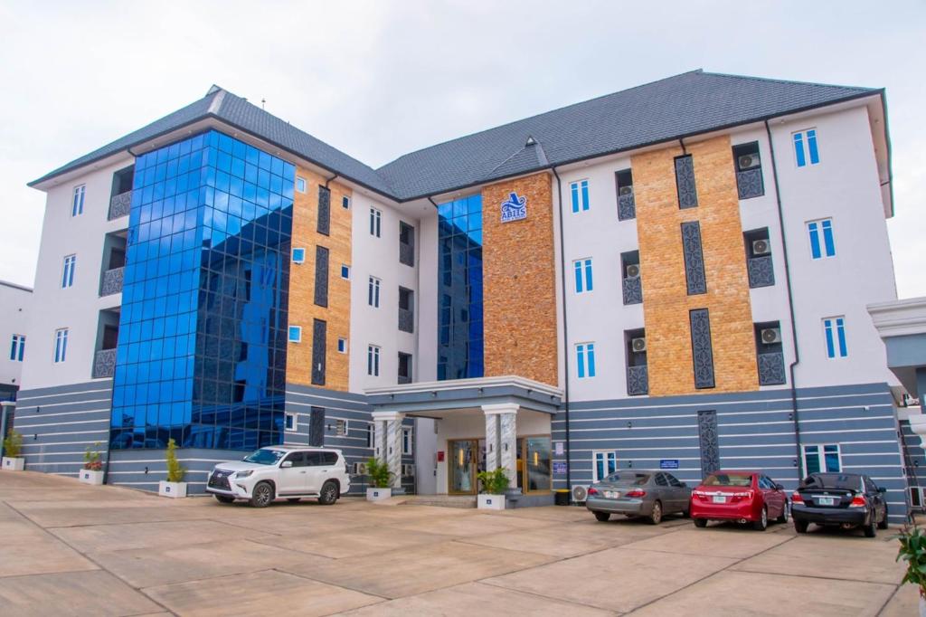 a large building with cars parked in a parking lot at Abiis Hotel and Suites in Abeokuta
