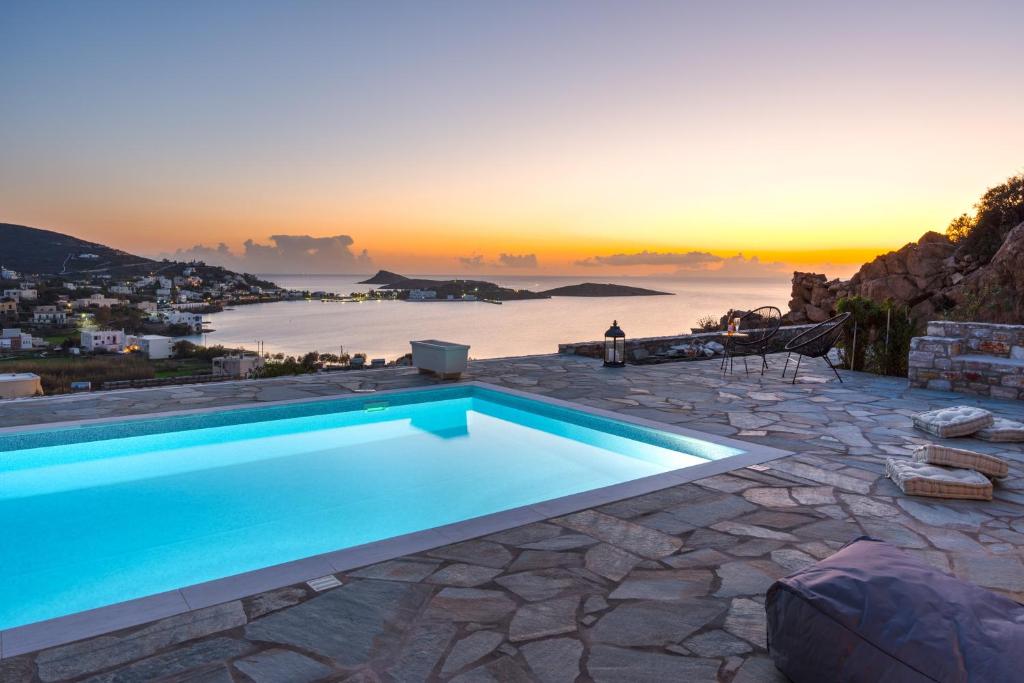 a swimming pool with a sunset in the background at Mont' Rock villas 1 in Posidhonía