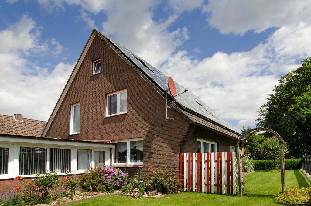 a brown brick house with a roof with a fence at Ferienhaus Gerda Wohnung 2 in Westochtersum