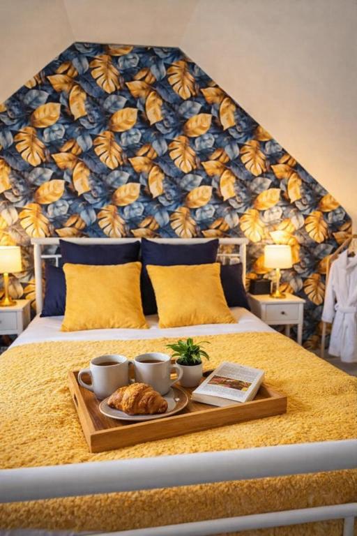 a bed with a tray of croissants and cups on it at Séjour près de Bayeux avec Massages et repas en options in Tilly-sur-Seulles