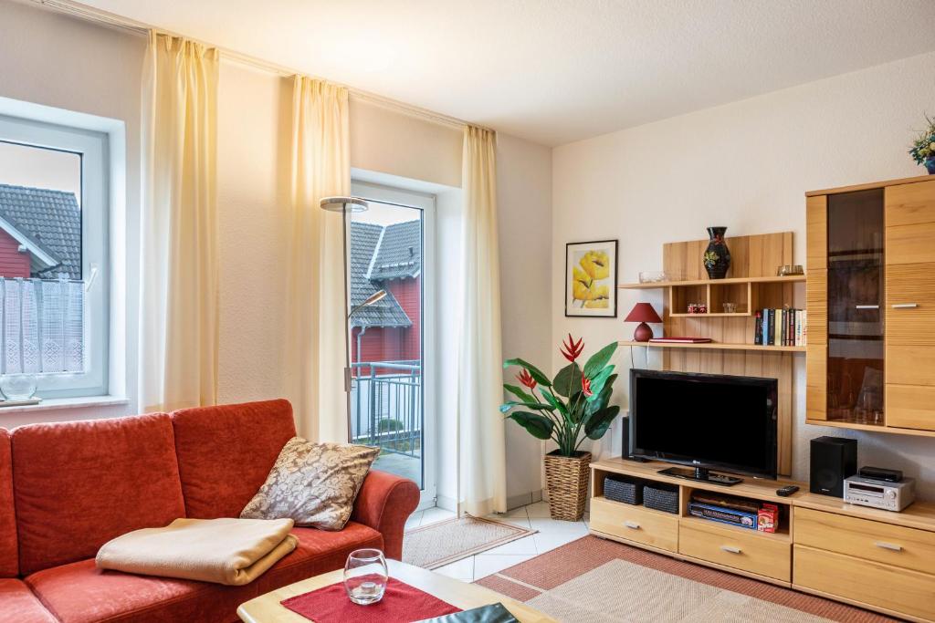 a living room with a red couch and a television at Ferienwohnung Tannenblick 3-2-3-3 in Oberhof