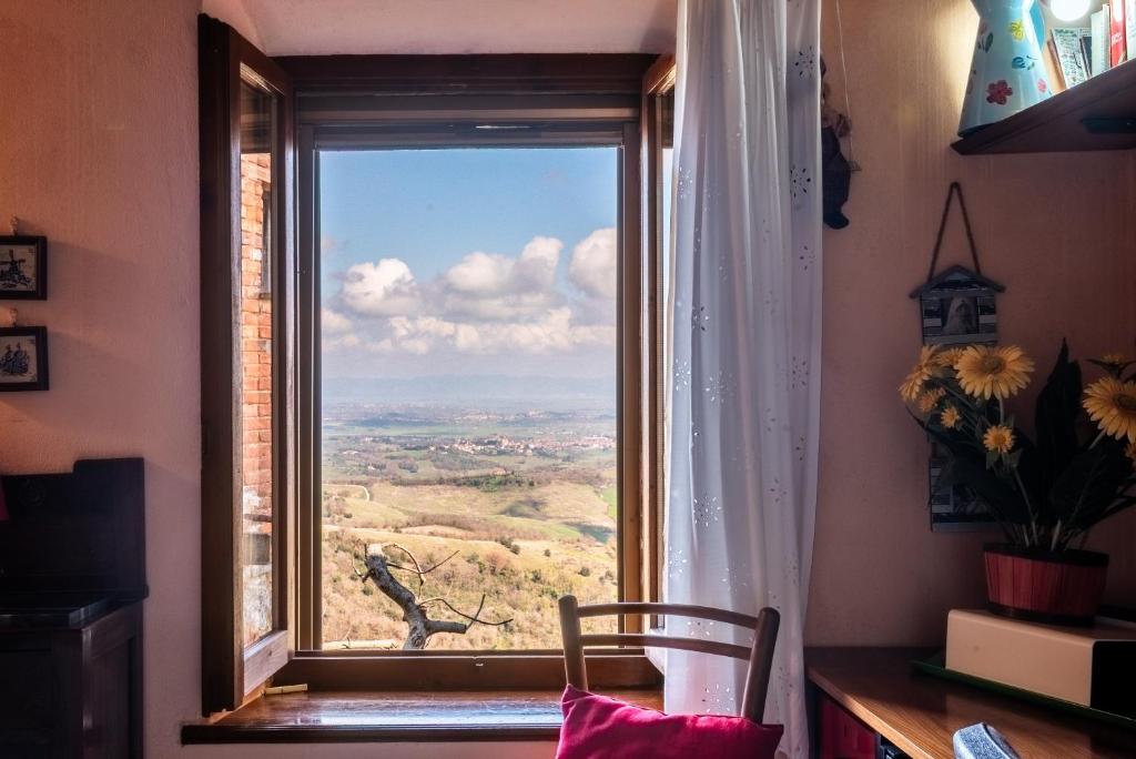 a window with a view of a field through it at Oasi del borgo Montefollonico in Montefollonico