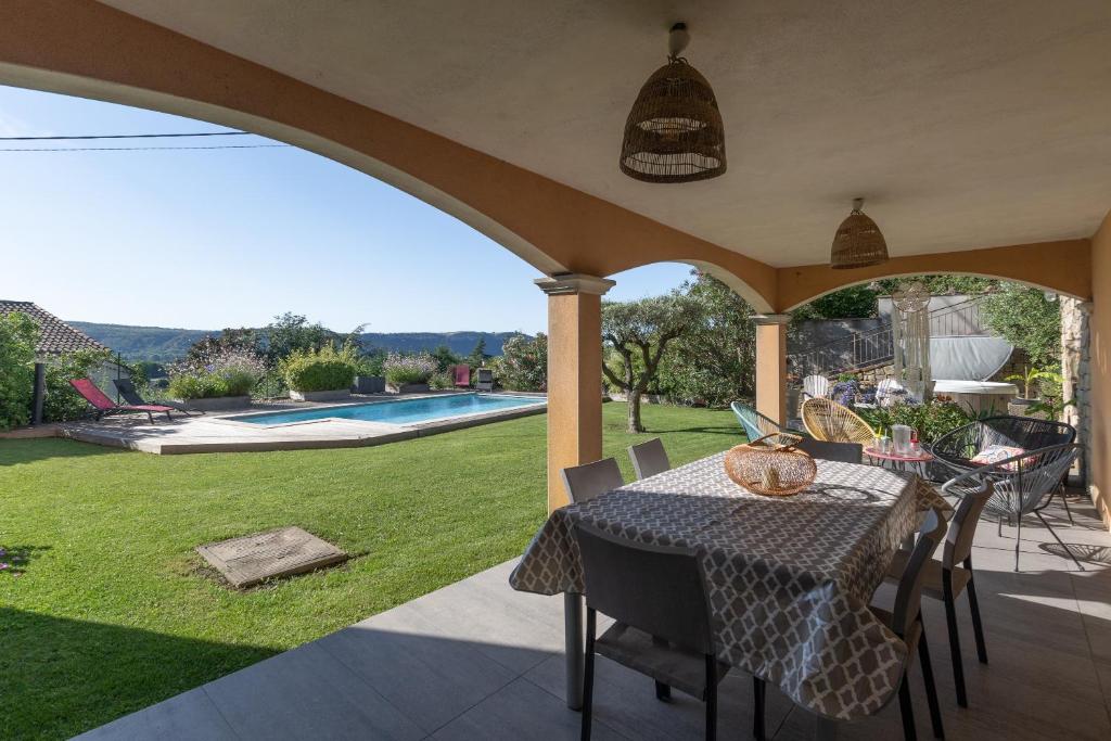 a patio with a table and chairs and a pool at Logement spacieux agréable in Saint-Privat
